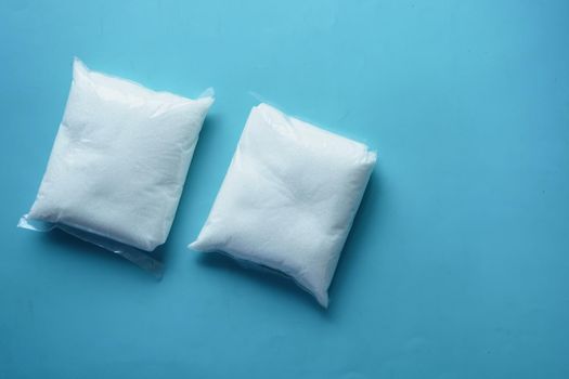 white sugar in a plastic packet on blue background ,