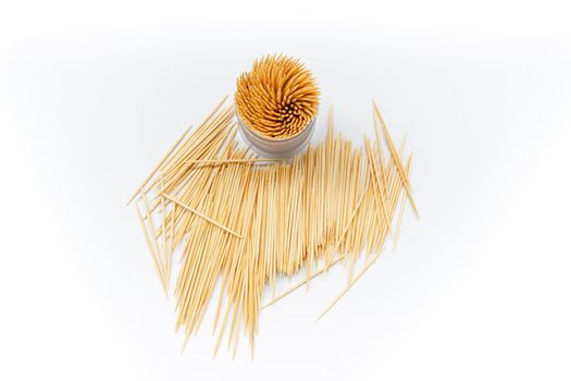 Pile of round wooden toothpicks and toothpick box with a plastic cover on white background. Directly above. Copy space.