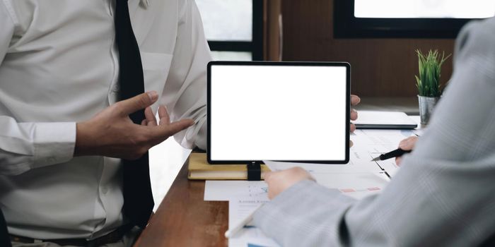 elegant attractive female office worker using mobile digital tablet with white blank screen showing report for colleague and her manager pointing to ask problem..