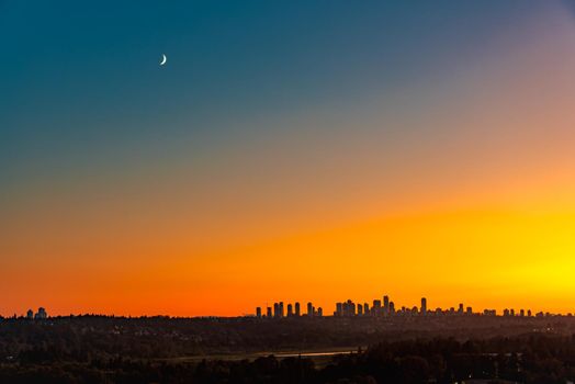 Metrotown district under the moon on sunset sky background.