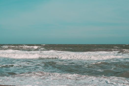 Ocean storm waves dramatically crashing splashing. Sky horizon line. Sea water edge, nature front view marine wallpaper, design. Bad weather cloudy overcast. Dark green turquoise blue tone pale matte.