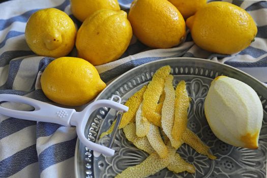 Lemon fruits and peeled strips for zest or making limoncello. Peeler, lemons and zest. Copy space, selected focus.