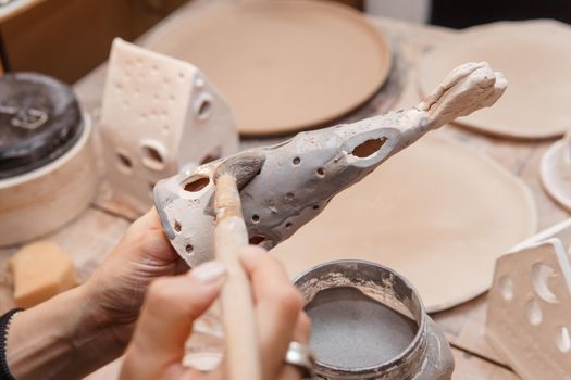 A master ceramist holds a clay product in his hands. Making a ceramic candle holder from clay. The process of coating the candlestick with glaze. Close-up.