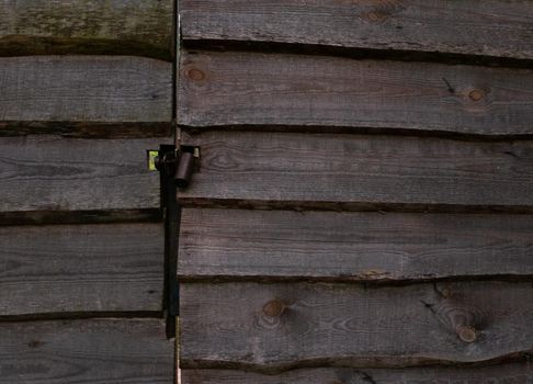 A wooden fence and a gate made of planks with a lock. Close up of sliding bolt.