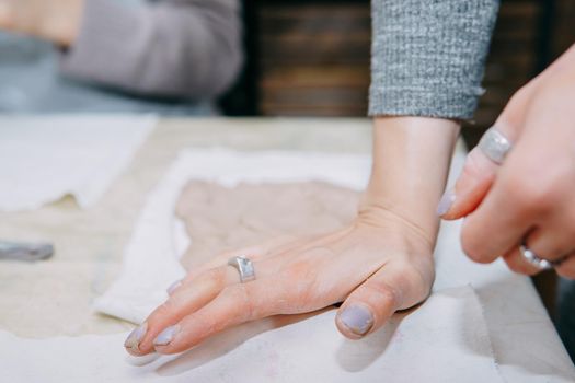 Female hands kneading clay. Production of ceramic products at the master class on ceramics. Close-up.