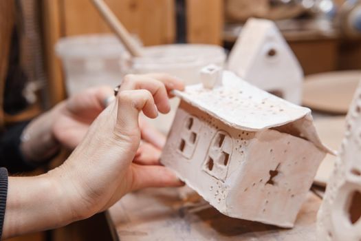 A master ceramist holds a clay product in his hands. Making a ceramic candle holder from clay. The process of coating the candlestick with glaze. Close-up.