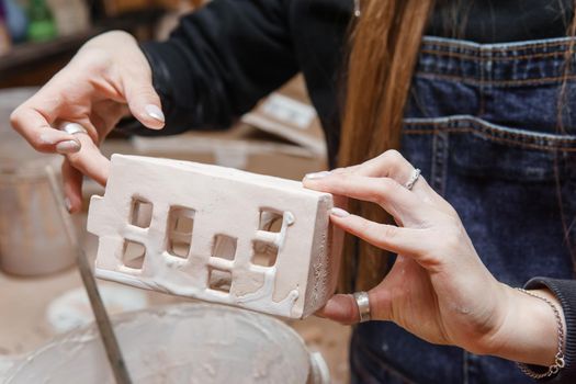 A master ceramist holds a clay product in his hands. Making a ceramic candle holder from clay. The process of coating the candlestick with glaze. Close-up.