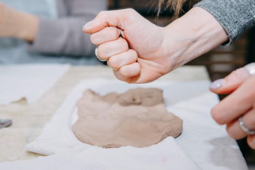 Female hands kneading clay. Production of ceramic products at the master class on ceramics. Close-up.