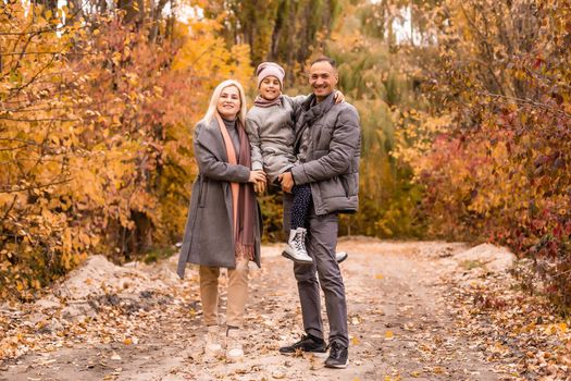 A Family of four enjoying golden leaves in autumn park.