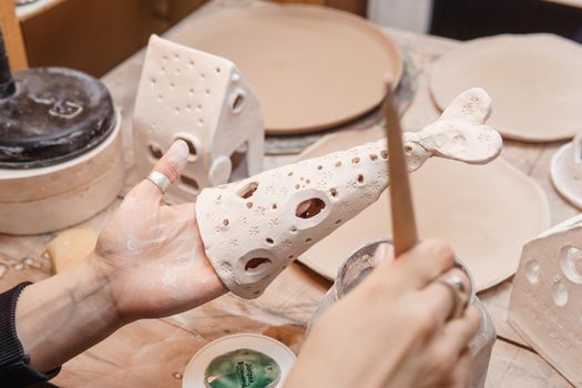 A master ceramist holds a clay product in his hands. Making a ceramic candle holder from clay. The process of coating the candlestick with glaze. Close-up.