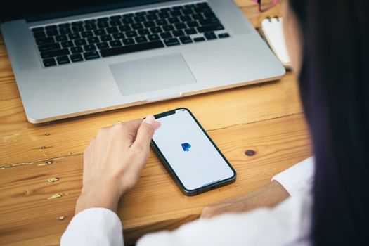 CHIANG MAI, THAILAND - MAY 30, 2021 : Women hands holding iphone with PayPal apps on the screen. PayPal is an online electronic payment system