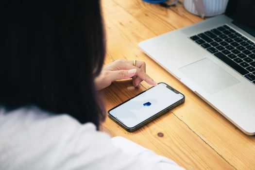 CHIANG MAI, THAILAND - MAY 30, 2021 : Women hands holding iphone with PayPal apps on the screen. PayPal is an online electronic payment system