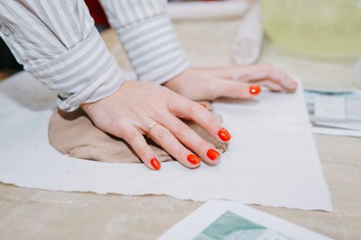 Female hands kneading clay. Production of ceramic products at the master class on ceramics. Close-up.