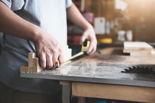 do-it-yourself concept Craftsmen use a tape measure to assemble wooden pieces to make wooden tables for customers