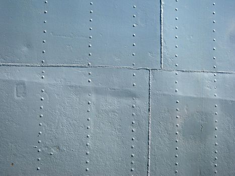 Detailed gray metal historic World War 2 ship wall with seams and rivets.