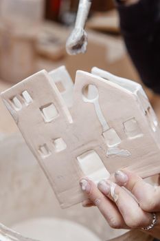 A master ceramist holds a clay product in his hands. Making a ceramic candle holder from clay. The process of coating the candlestick with glaze. Close-up.