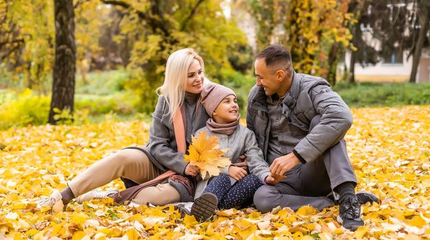 Young happy family while walking in the autumn park
