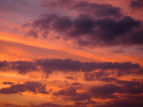 Sunset casts red light into the clouds stretching into the distance from high above.  Beautiful cloudscape for background or texture.