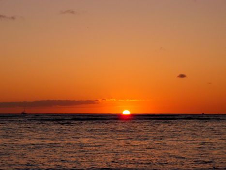 Sunset over the horizon of Pacific Ocean in Waikiki with boats in the water of Oahu, Hawaii.