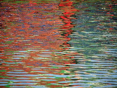 Red Blue Color pattern shimmers and reflects in ripples of water making a psychedelic pattern.