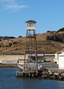 Tall Lookout Tower at San Quentin State Prison California along the water with hill in the background.
