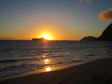 Early Morning Sunrise on Waimanalo Beach over Rabbit Island bursting over the island on Oahu, Hawaii.