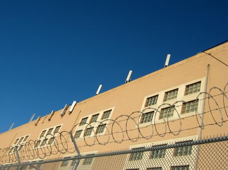 Cell Towers line top of Building in San Francisco, California,  with blue sky and behind barbwire fence.  