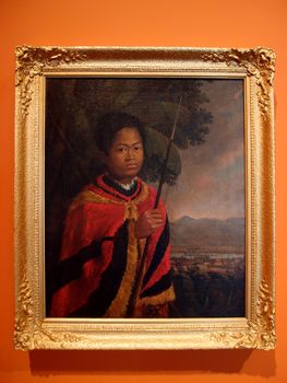 Kamehameha III, 1825, Oil on canvas by Robert Dampier (British, 1800-1874).  Posed as the monarch he was destined to become, young Kamehameha stands regally in a verdant setting,  the small settlement of Honolulu fort just visible beyond the banana trees that frame him.    Holding a spear, he is draped in a traditional feather garment.  Kamehameha III reigned from  1825 to 1854, during which time he oversaw Hawaii transition from a feudal society to a constitutional monarchy.