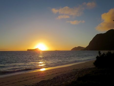 Early Morning Sunrise on Waimanalo Beach on Oahu, Hawaii over Rabbit Island bursting light across the bay and sky.