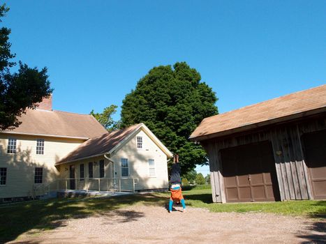 Man wearing a hat, long sleeve t-shirt, pants, and slippers Handstands at Historic Jonathan Trumbull jr. House Museum in lebanon, connecticut.