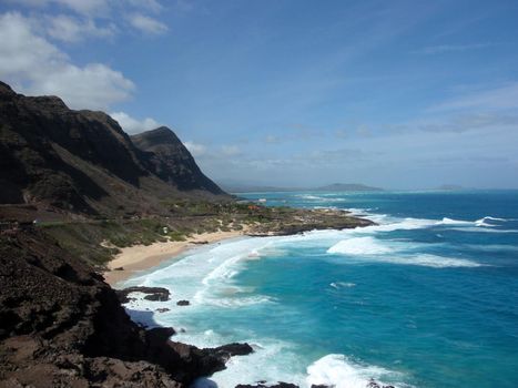 Waves crash on Makapuu Beach with the Koolau Range Mountains above looking towards Waimanalo Bay on the Windward coast of Oahu, Hawaii.