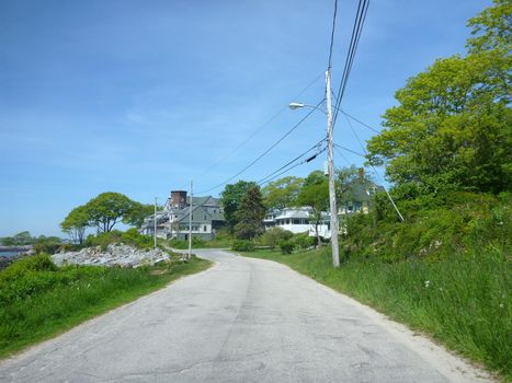 Road lined powerlines and trees with houses in the distance on Peak Island in Portland Harbor, Maine.