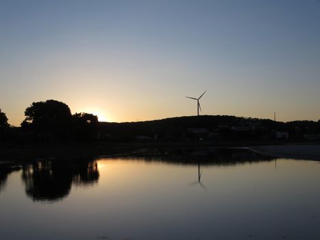 Sunsets over Stream leading to beach with windmill visible above the trees at Good Harbor Beach, Gloucester, Massachusetts. 