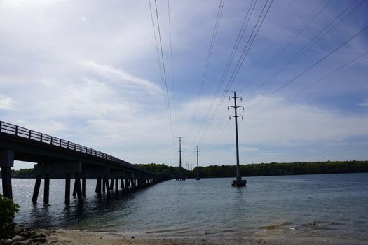 Bridge and Power lines cross waterway connecting beach on Cousins Island to the mainland of maine.