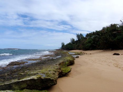 Beach with tide pool and large rocks in San Juan, Puerto Rico on a beautiful day.