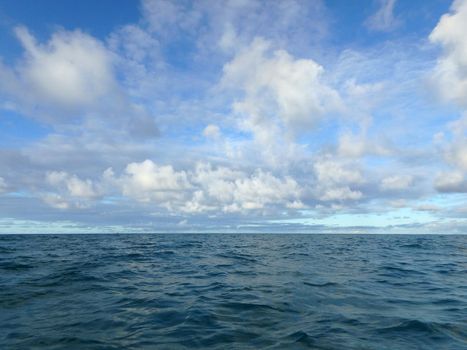 Shallow wavy ocean waters of Waimanalo bay looking into the pacific ocean with a blue sky full of clouds at dusk on Oahu.