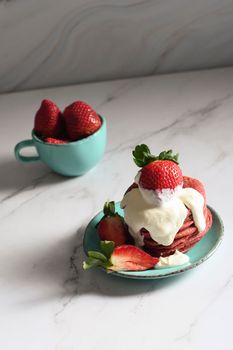 still life with pink strawberry pancakes on a turquoise plate with sour cream and fresh strawberries, cultural exotic food, creative breakfast for Valentine's holiday against a turquoise vase