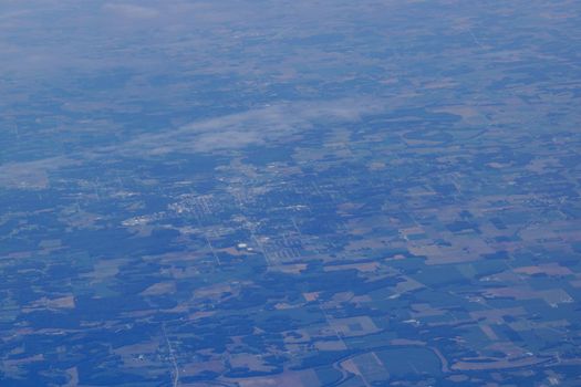 aerial photograph of small city town in Eastern USA with fields, river, houses, clouds, and roads from high above.