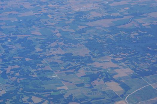 aerial photograph of rural Eastern USA with fields, river, houses, and roads from high above.