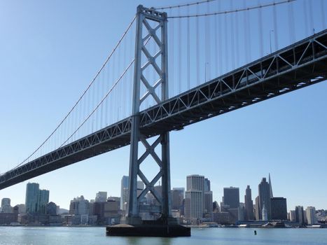 Bay Bridge and Downtown San Francisco Cityscape, with iconic ferry building visible, seen from the water. 