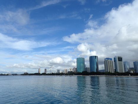 Glassy water of Ala Moana Beach with Condo buildings and construction cranes in the distance during a beautiful day on the island of Oahu, Hawaii. 