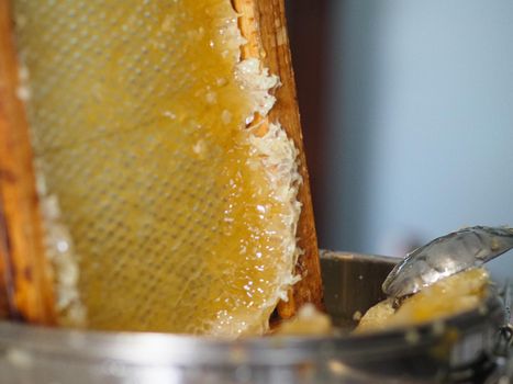 Natural raw honey being filtered ad dripped through a strainer to filter our bees wax.