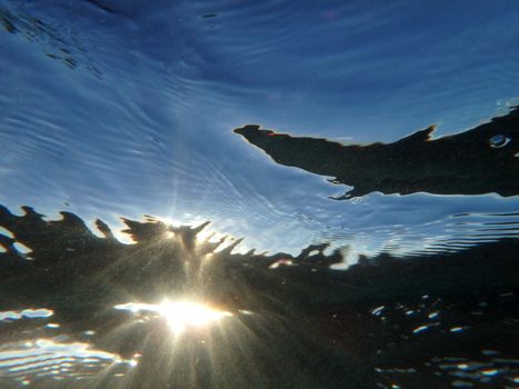 Sun light underwater with wave ripples and particles of sand.