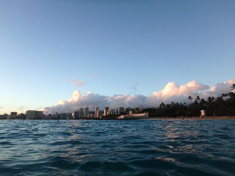 Dramatic Dusk scape over historic Natatorium, Waikiki and San Souci Beach with people on the beach, coconut trees and lifeguard tower on a nice day Oahu, Hawaii.