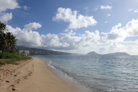 Sandy shoreline of Kahala Beach and the southern coastline of Oahu, Hawaii on a beautiful day.