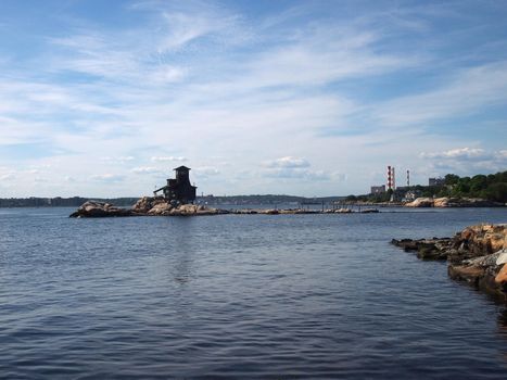 House on Hobs Island in the Thames River as it opens to the sea at Groton Beach looking back towards Connecticut with power plant and homes in the distance.