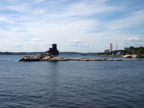 House on Hobs Island in the Thames River as it opens to the sea at Groton Beach looking back towards Connecticut with power plant and homes in the distance.