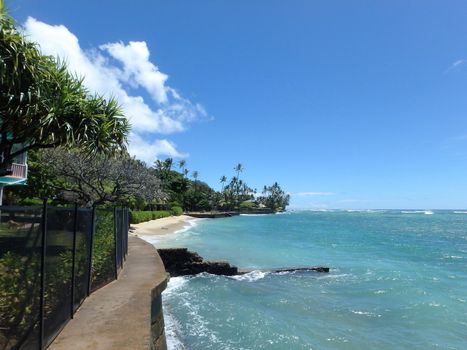 Makalei Beach Park with seawall, coconut trees, homes on Oahu, Hawaii.