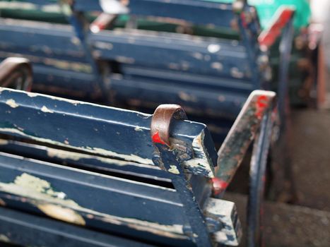 Old Baseball park seat with chipping blue paint with white and red layers underneath beginning to be revealed in Fenway park.