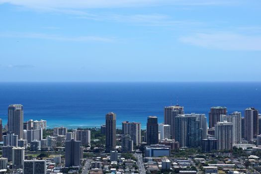 Waikiki and Honolulu cityscape, McCully street leading into Waikiki, roads, buildings, skyscrapers, parks, and Pacific Ocean with boats in the water and clouds in the sky on Oahu, Hawaii. Metropolitan.